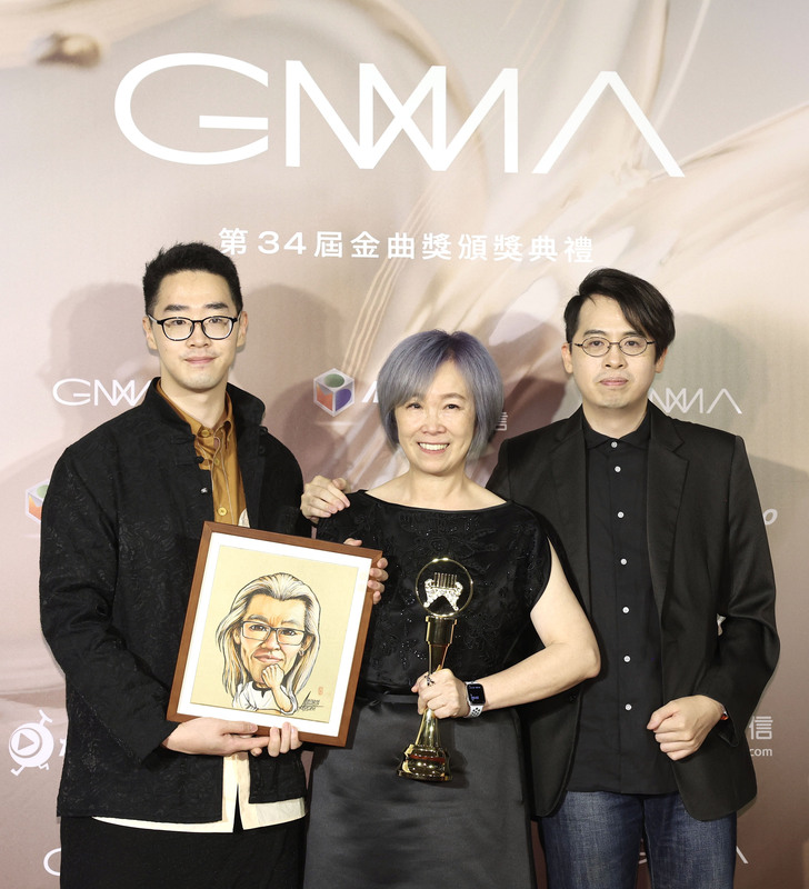 金曲獎睽違3年重回台北小巨蛋舉行頒獎典禮，1日晚間盛大登場，已故作詞人林秋離榮獲第34屆特別貢獻獎，妻子熊美玲(中)與兒子林雨果(右)、林語堂(左)帶著林秋離的畫像代為領獎。(圖：中央社)