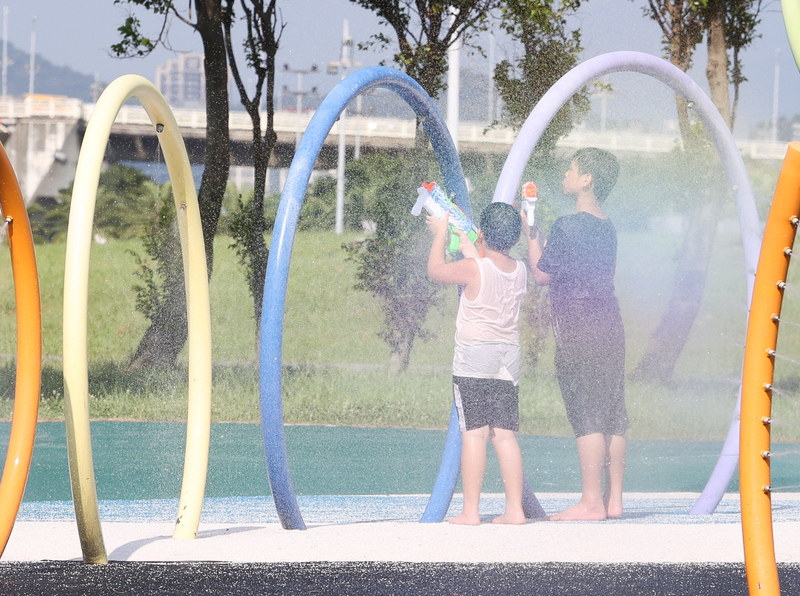 氣象局發布高溫資訊。圖為小朋友在台北大佳河濱公園戲水消暑。(圖：中央社)