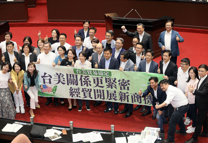 立法院臨時會院會26日無異議通過「台美21世紀貿易倡議」首批協定，民進黨立委柯建銘（2排右8）、劉世芳（2排左6）與莊瑞雄（2排右7）等人在議場內持標語開心合影。 (圖：中央社)