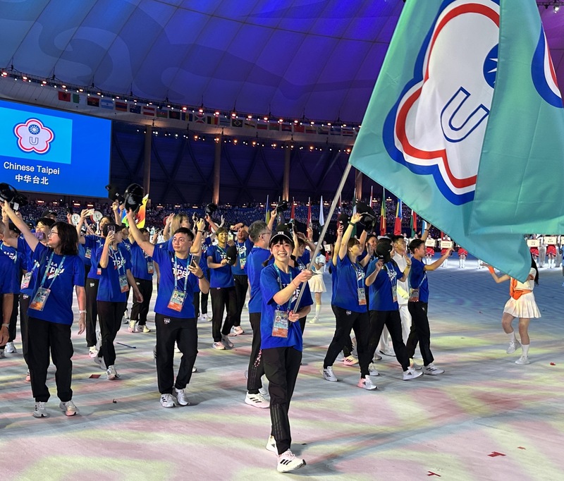 第31屆成都世大運28日晚舉行開幕儀式，台灣代表隊由「排球甜心」廖苡任（前）擔任掌旗官，率領65人進場。（大專體總提供） (圖：中央社)