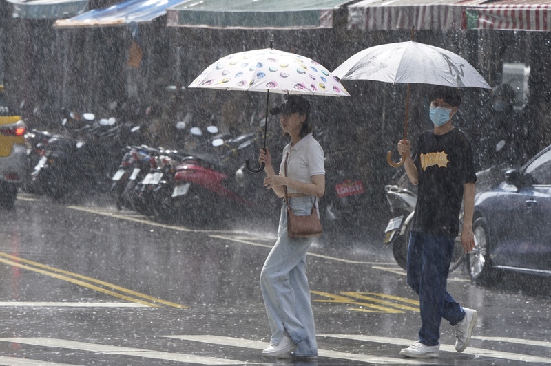 圖為台北市迪化街，民眾遇大雨撐傘過馬路。(資料照片/CNA)