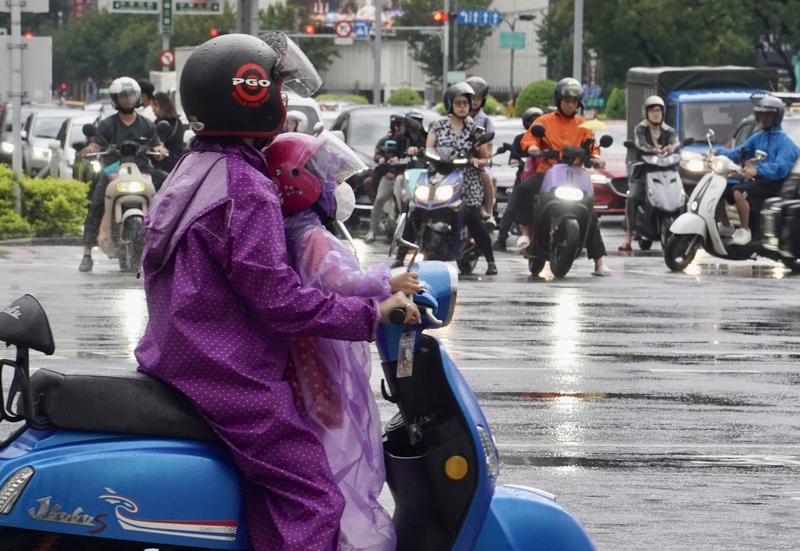 中央氣象局指出，17日各地降雨機率高，中南部留意強降雨。圖為高雄市新興區16日近傍晚時分出現陣雨，許多機車騎士穿上雨衣因應。 (圖：中央社)