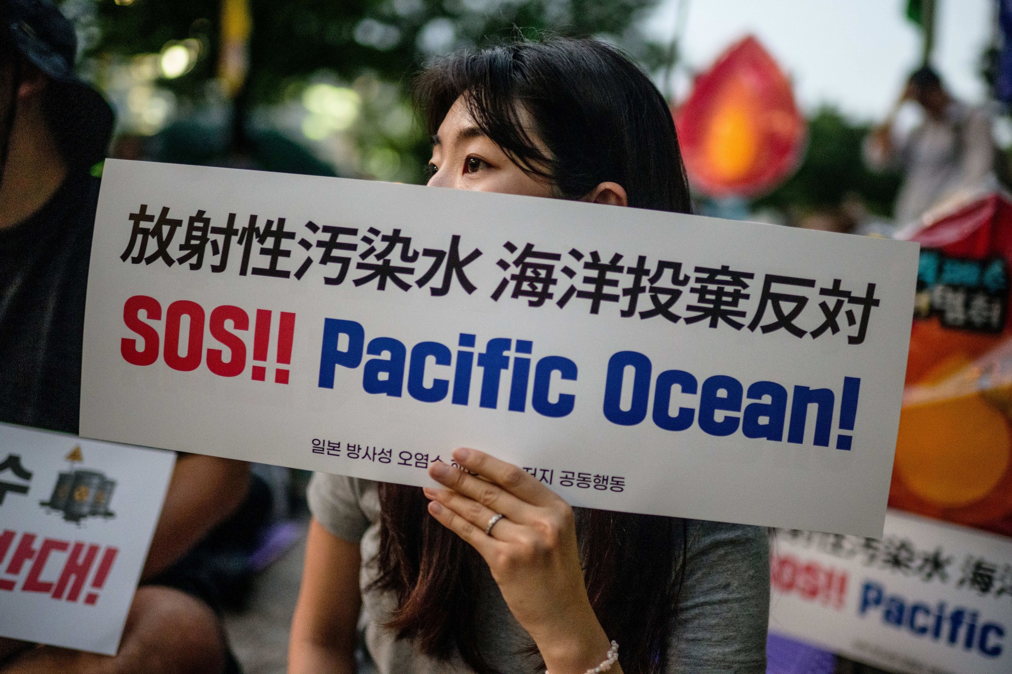 南韓一名民眾手持一塊寫有「SOS!! 太平洋！」的標語，在首爾市政廳外抗議日本福島核處理水排放到太平洋。(AFP)