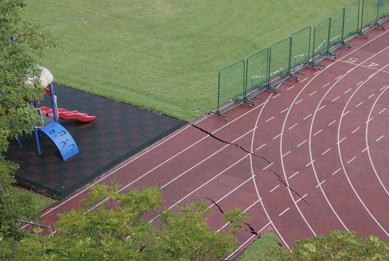 台北市中山區大直街巷弄多棟大樓7日疑因周邊建案開挖而傾斜，工地緊鄰學校的部分操場也受影響，跑道出現龜裂狀況。 (圖：中央社)