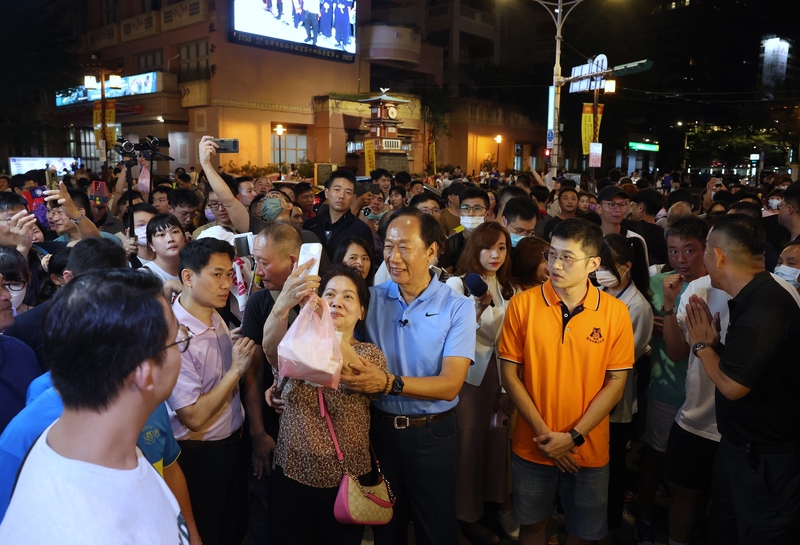 鴻海集團創辦人郭台銘（前中藍衣者）9日晚間走訪台北饒河街觀光夜市，吸引群眾關注，有不少人熱情上前要求合影，郭台銘也展現親和力與民眾互動。 (圖：中央社)