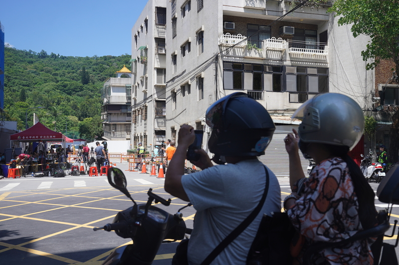 基泰鄰損案居民不敢返家，北市府表示可住旅館至25日  是否延長再議。圖為路過民眾在管制區外拿手機拍攝。(圖：中央社)