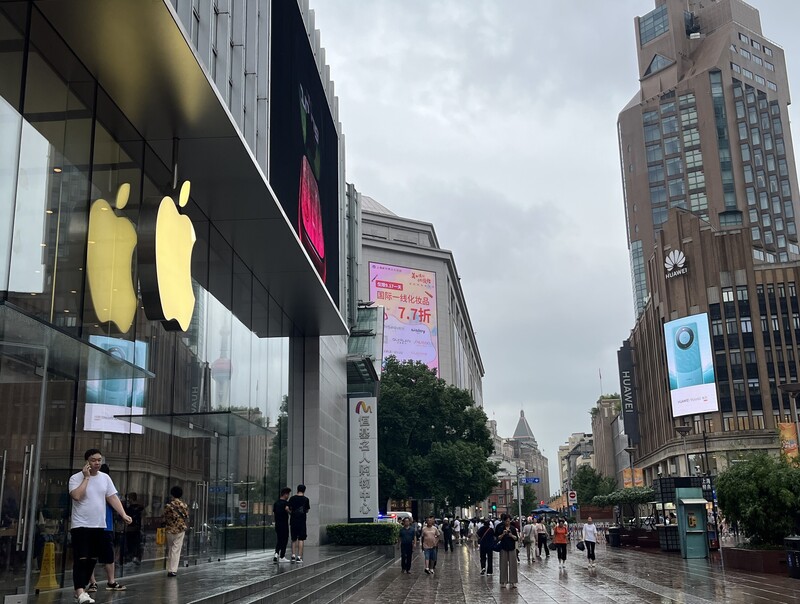 華為Mate 60系列、蘋果iPhone 15系列相繼推出後，「你選華為或蘋果」成為中國社群話題，相關討論不脫離中美科技競爭氛圍。圖為上海市南京東路場景，蘋果零售店斜對面街口為華為旗艦店座落地點，中間相隔一條橫向馬路。 (圖：中央社)