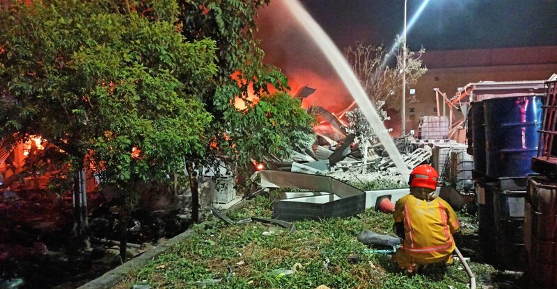 明揚國際公司位於屏東的工廠22日發生火警爆炸意外，造成嚴重傷亡。大火延燒冒出陣陣火光，消防員持續射水降溫滅火。（屏東消防局提供） (圖：中央社)