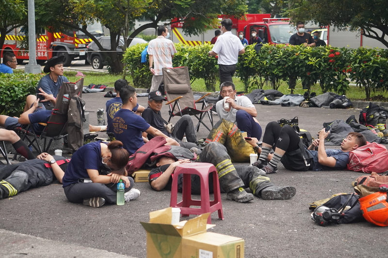 屏東科技產業園區明揚國際科技公司22日發生火警，第一線消防人員徹夜救火，幾乎沒有時間休息。有消防員23日暫時卸下裝備，疲憊不堪席地而睡。 (圖：中央社)