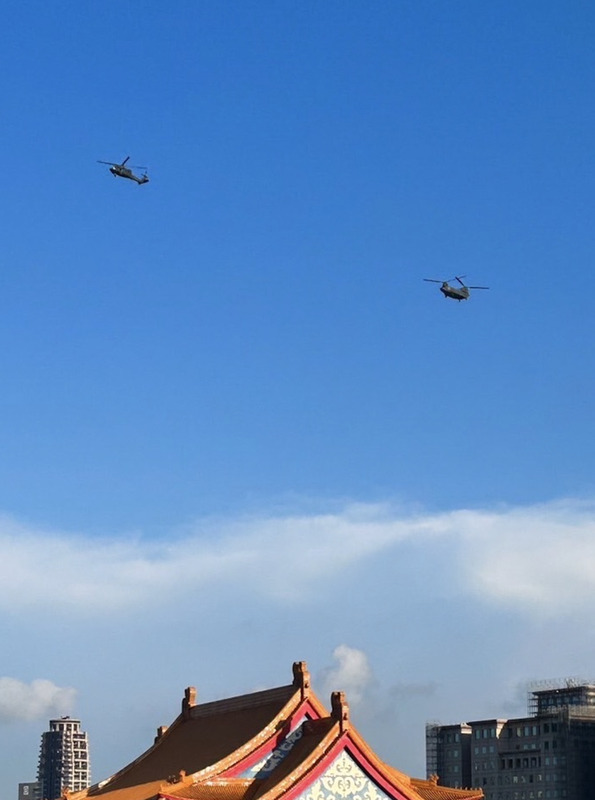 國慶將至，國軍26日進行半兵力預演，其中1架UH-60M黑鷹直升機（左）與游懸掛巨幅國旗的CH-47SD契努克運兵直升機（右）通過總統府上空。 (圖：中央社)