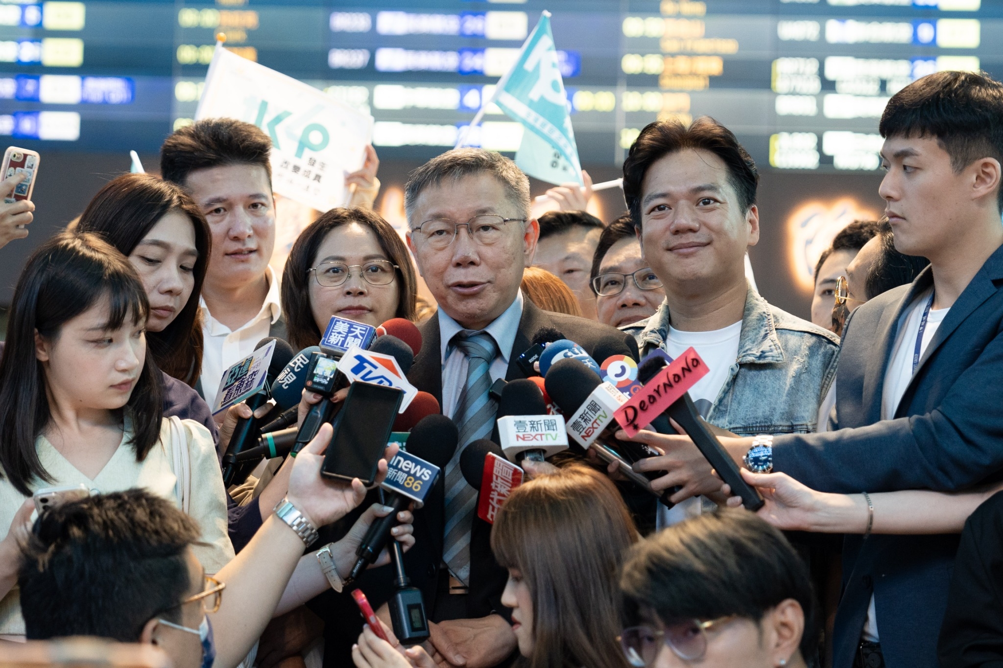 民眾黨總統參選人柯文哲(中)1日啟程二度訪美，在機場接受訪問時表示，藍白要合作就來比民調。(民眾黨提供)