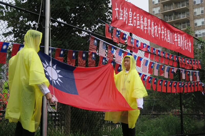 紐約市皇后區僑界7日在雨中舉行雙十國慶升旗典禮，僑務委員會海外青年文化大使協會(FASCA)學員擔任的旗手身穿雨衣。 (圖：中央社)