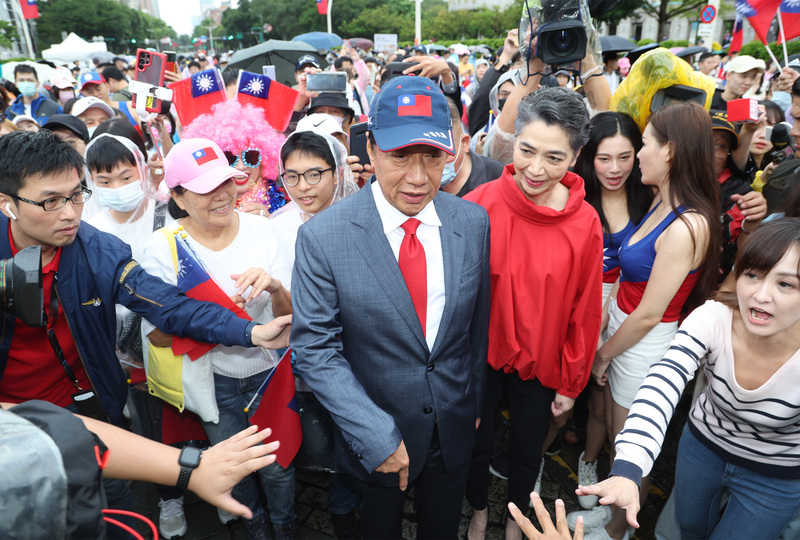 雙十國慶，爭取獨立參選2024總統的鴻海創辦人郭台銘（紅領帶）與副手人選賴佩霞（紅衣）10日上午在支持者簇擁下走入台北市政府前廣場，參與北市府國慶升旗典禮。 (圖：中央社)