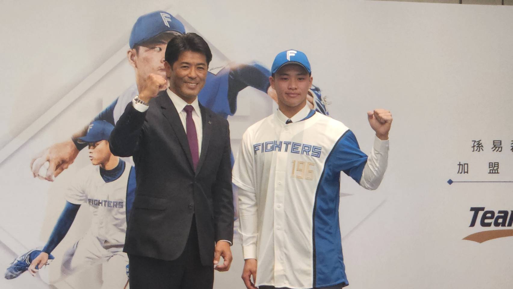 U18世界盃棒球賽台灣王牌投手孫易磊(右)，16日正式加盟日本火腿鬥士隊，球隊GM（總經理）稻葉篤紀(左)更親自來台為孫易磊披上背號196號球衣、戴上球帽，表達重視。(江昭倫 攝)