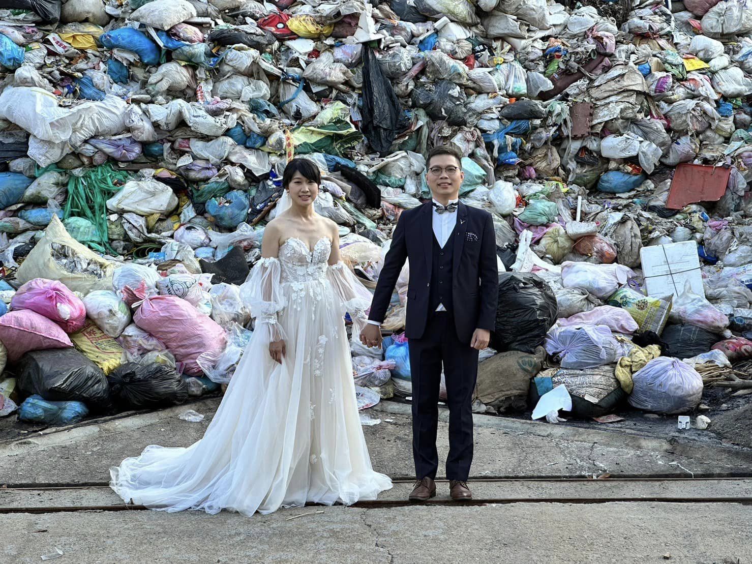 一對台灣新人穿著燕尾服和婚紗，在垃圾山前拍下一張非正統的結婚照。 (圖:取自臉書)