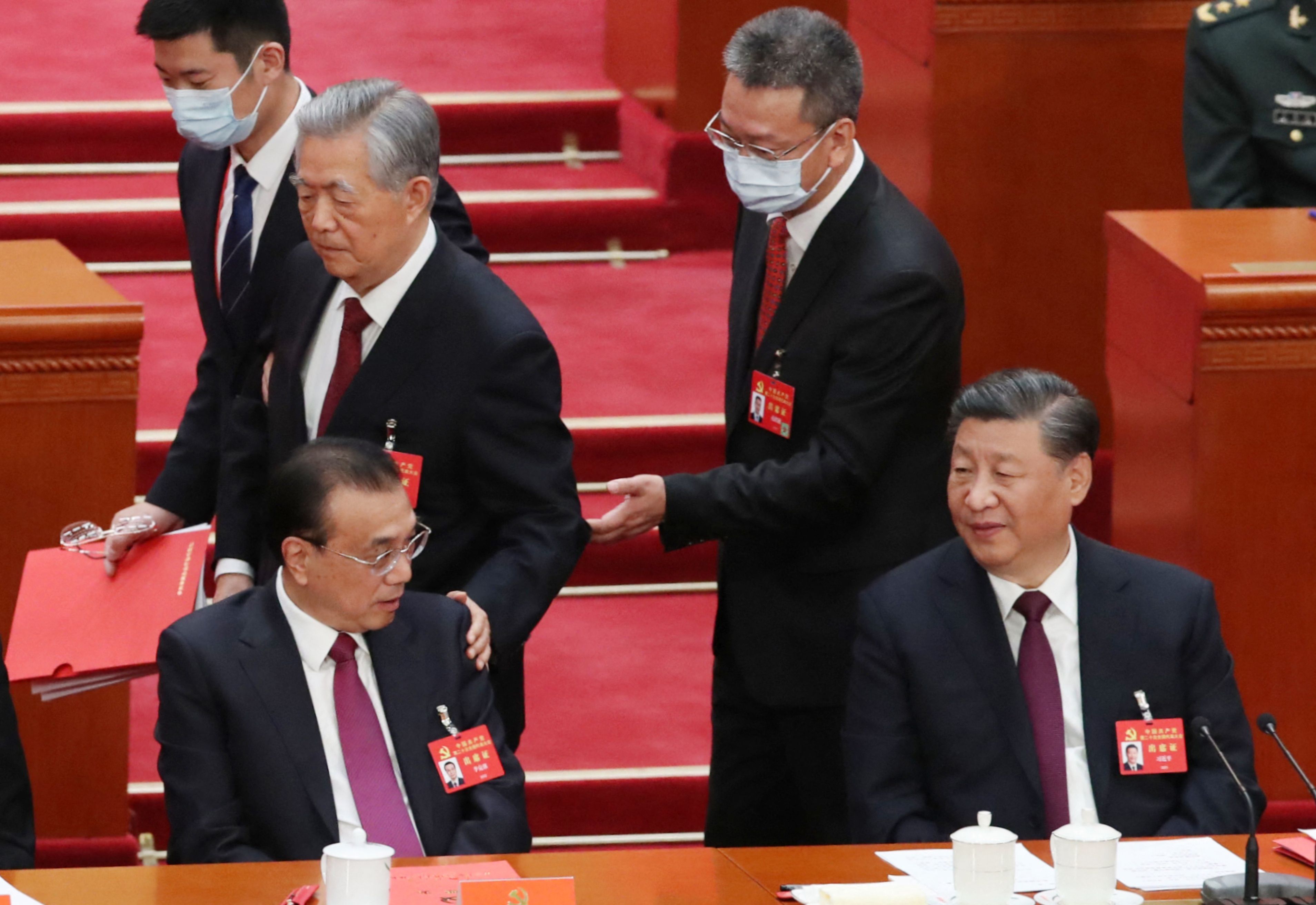 2022年10月22日二十大閉幕，胡錦濤被請離會場，經過李克強身邊時，特意拍拍他的肩膀，前右為中國國家主席習近平。 (AFP)