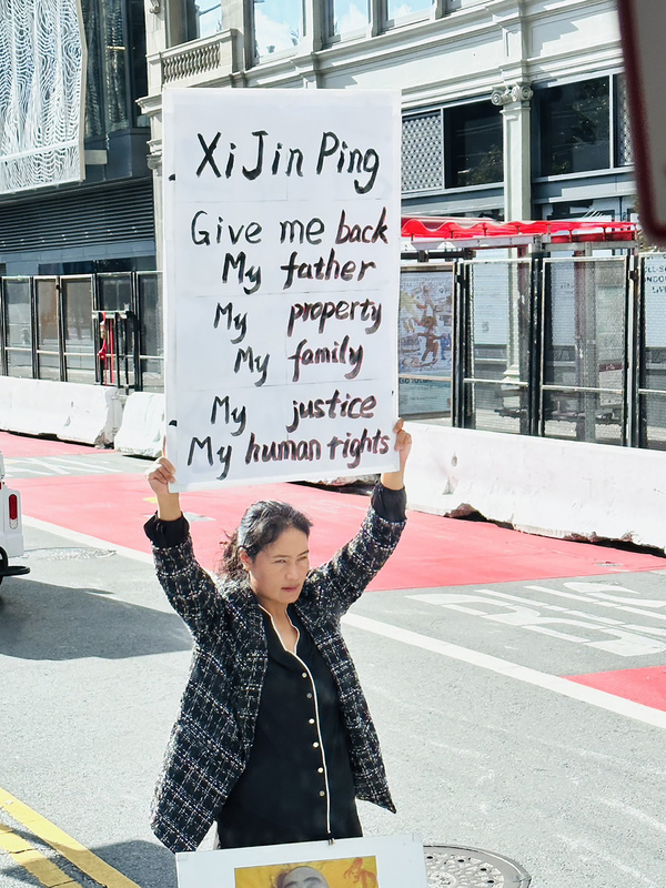 亞太經濟合作會議（APEC）11日展開，21個經濟體成員領袖將陸續抵達舊金山。圖為會場附近有一名華裔女性高舉「習近平還我財產、還我家園、還我父親」標語牌，表達訴求。（APEC台灣媒體團提供） (圖：中央社)