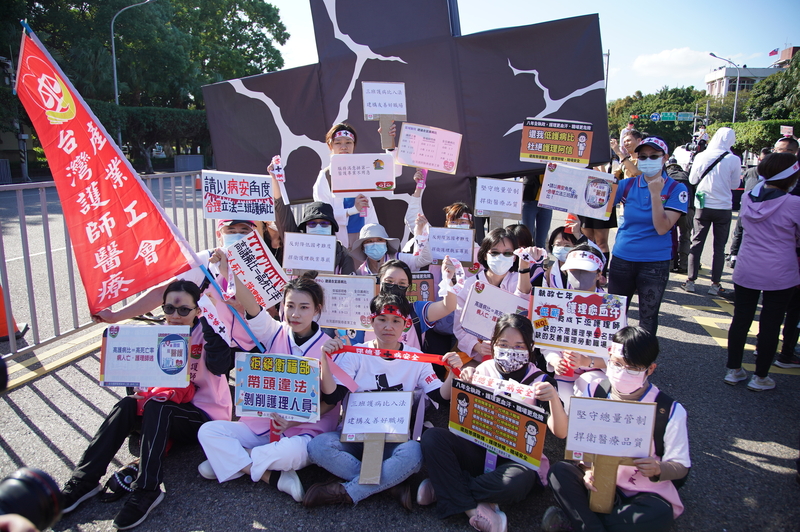 台灣醫事人員大聯盟19日在凱達格蘭大道發起「黑十字運動」，舉起標語表達訴求。(圖：中央社)