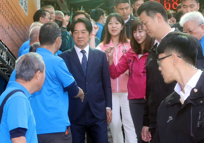 民進黨總統參選人賴清德（中左，西裝者）7日前往松山慈惠堂參香祈福，結束後與廟外歡迎民眾握手致意。(圖：中央社)