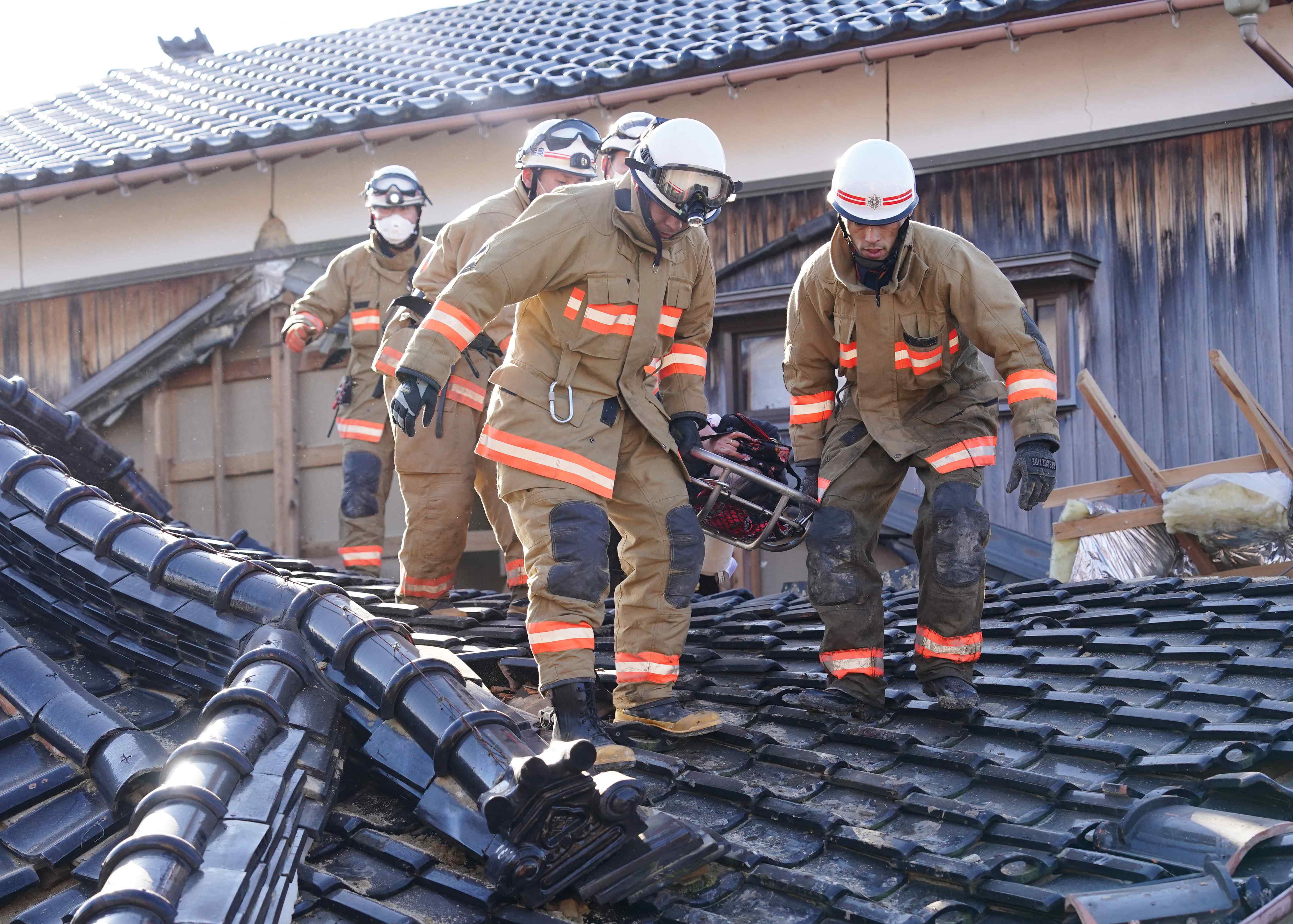 援救人員從石川縣珠洲市一棟倒塌的房屋中，救出一名婦人。(讀賣新聞/AFP)
