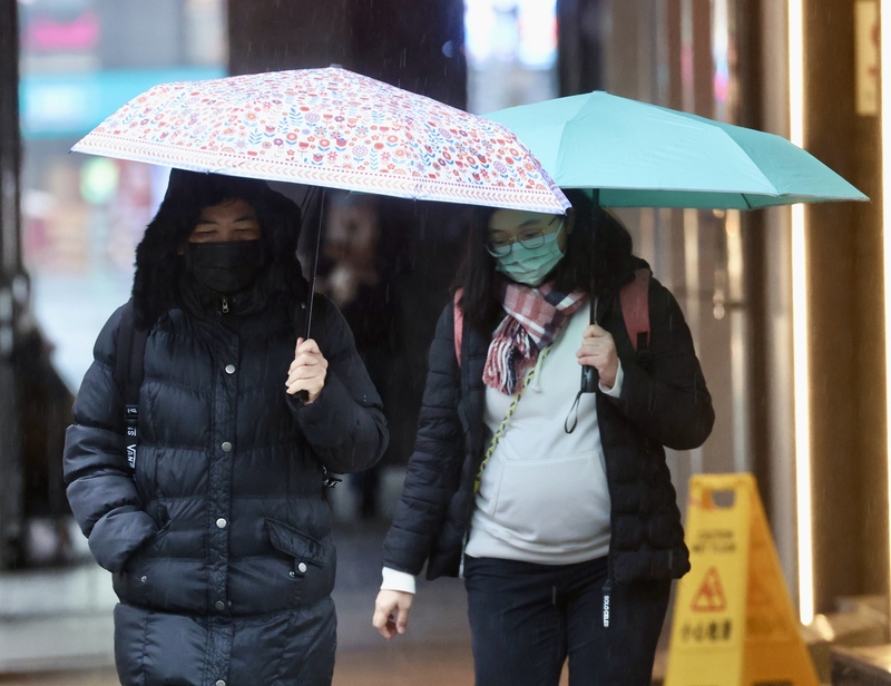 今天(23日)新一波大陸冷氣團挾帶更為潮濕的冷空氣南下報到，北部及東北部普遍都是濕冷的天氣型態，但南部地區氣溫仍可達26度。圖為台北市中正區外出民眾穿著厚外套，撐傘擋雨。 (圖：中央社)