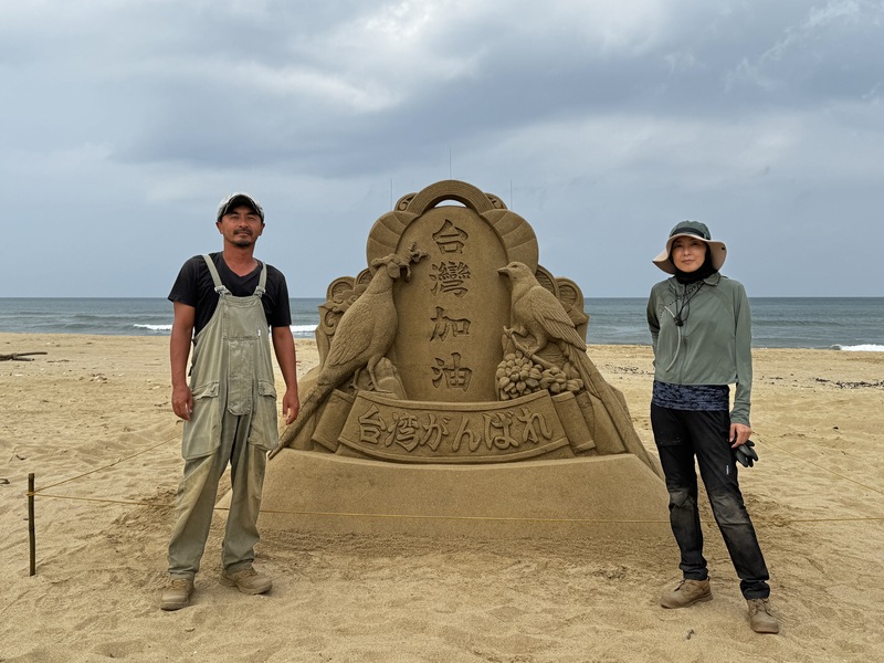 日本沙雕師保坂俊彥（左）和林真理（右）在新北市貢寮區福隆海水浴場沙灘打造沙雕作品「台灣加油」，要為花蓮地震災民打氣。(圖：中央社)