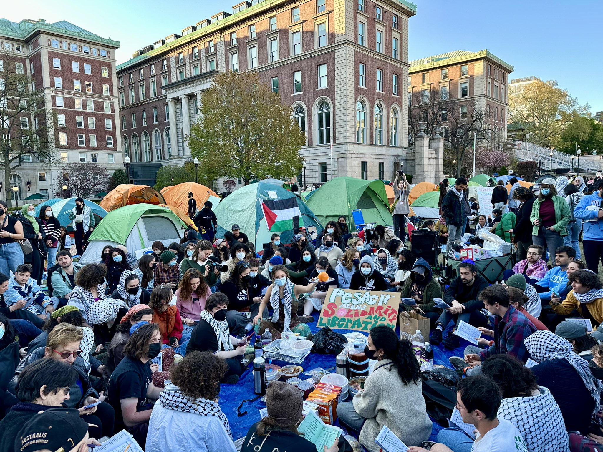 哥倫比亞大學學生在校園草坪建立的「加薩團結營地」(Gaza Solidarity Encampment)，抗議加薩戰爭，可見許多人都戴上口罩。(圖取自X平台)