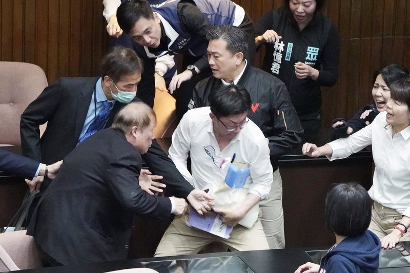 立法院會17日處理藍白所提國會改革法案，朝野多次爆發衝突，民進黨立委郭國文（前中白衣者）下午一度上前搶走立法院秘書長周萬來（前左）手中提案資料，周圍眾人目睹傻眼。(圖：中央社)