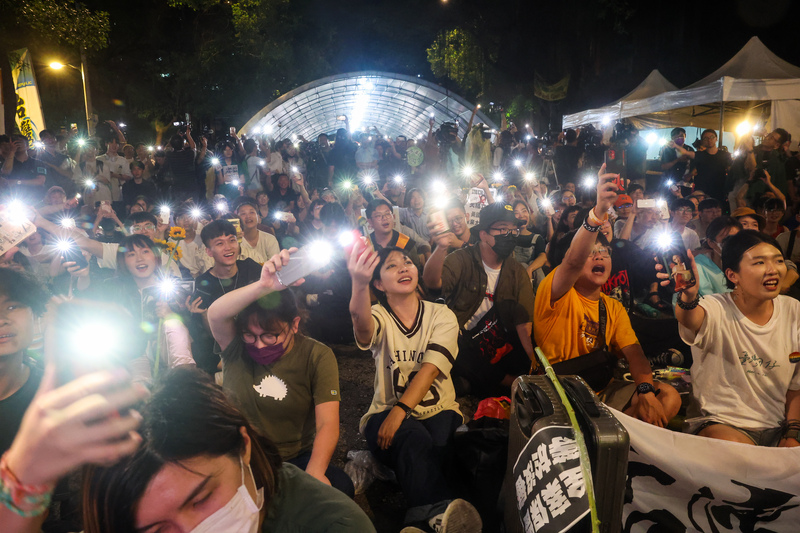 立法院會21日挑燈夜戰處理國會職權相關修法，大批民眾同樣集結在院外關注議場動態，晚間青島東路上聚集群眾揮舞手機燈光，齊聲唱起歌曲「島嶼天光」。 (圖：中央社)