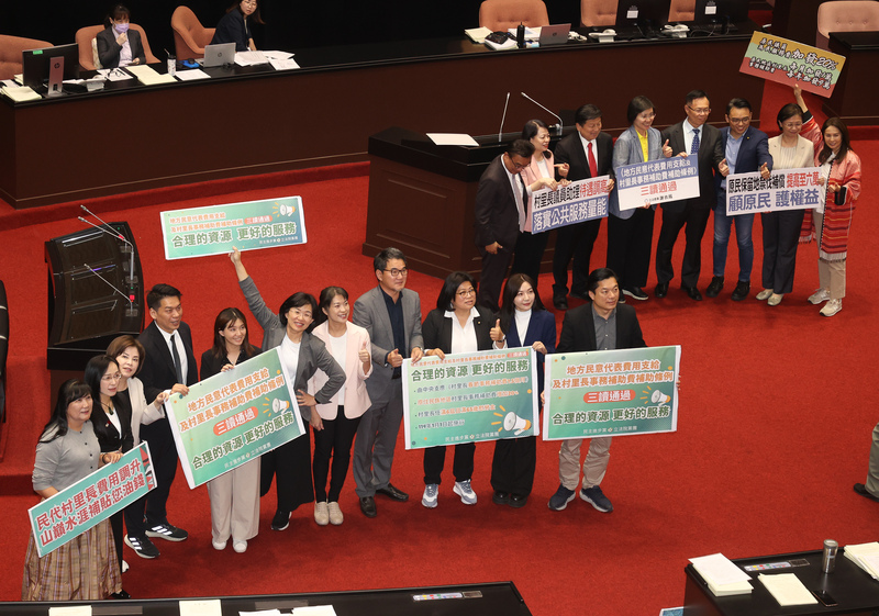 立法院會4日三讀修正通過地方民意代表費用支給及村里長事務補助費補助條例部分條文，增訂村里長春節加發1.5個月事務補助費，朝野立委在議場舉標語合影表達支持。(圖：中央社)