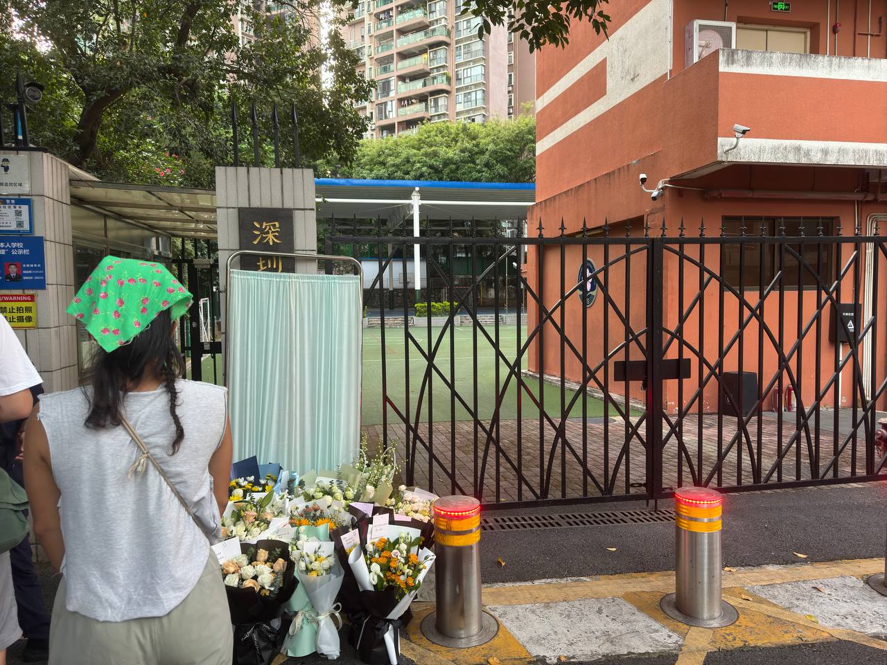 深圳日本人學校門口，在一名學童遇刺身亡後，學校招牌已被遮蔽，許多民眾到場獻花，但花束不久後即被清空。(X平台/@whyyoutouzhele)