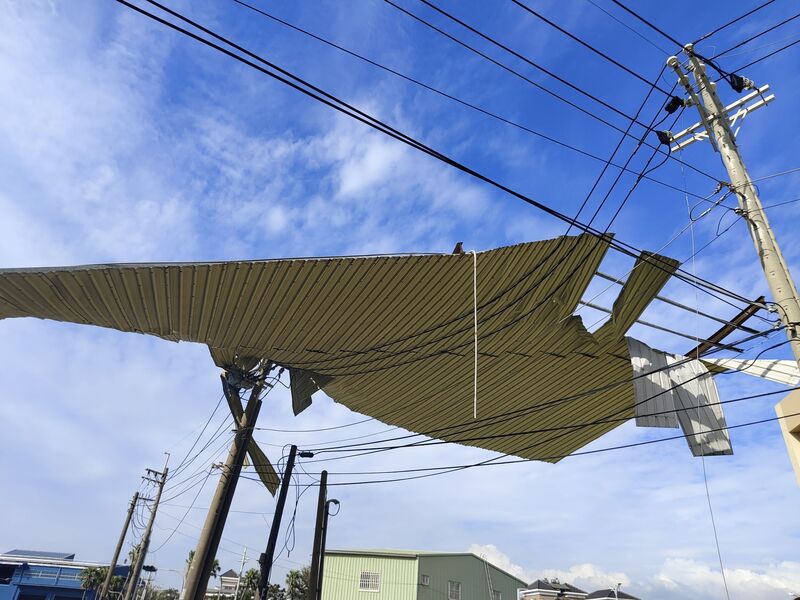 颱風山陀兒造成全台累計43萬戶停電，台電3日起啟動工作班跨縣市支援，剩餘1.2萬戶拚今天復電。圖為被風吹落的鐵皮屋頂落在電纜線路上方。(圖：中央社)