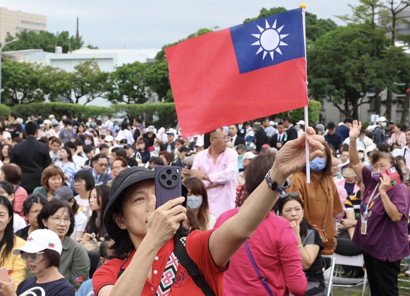 中華民國中樞暨各界慶祝113年國慶大會10日在總統府前廣場舉行，與會民眾高舉國旗拍照留念(圖：中央社)