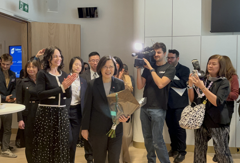前總統蔡英文17日午間來到歐洲議會大樓，進入接待沙龍後獲得約50位議員熱情歡迎的掌聲，主持接待的議員萊克斯曼（蔡身旁著黑衣鼓掌者）並獻上花束。 (圖：中央社)