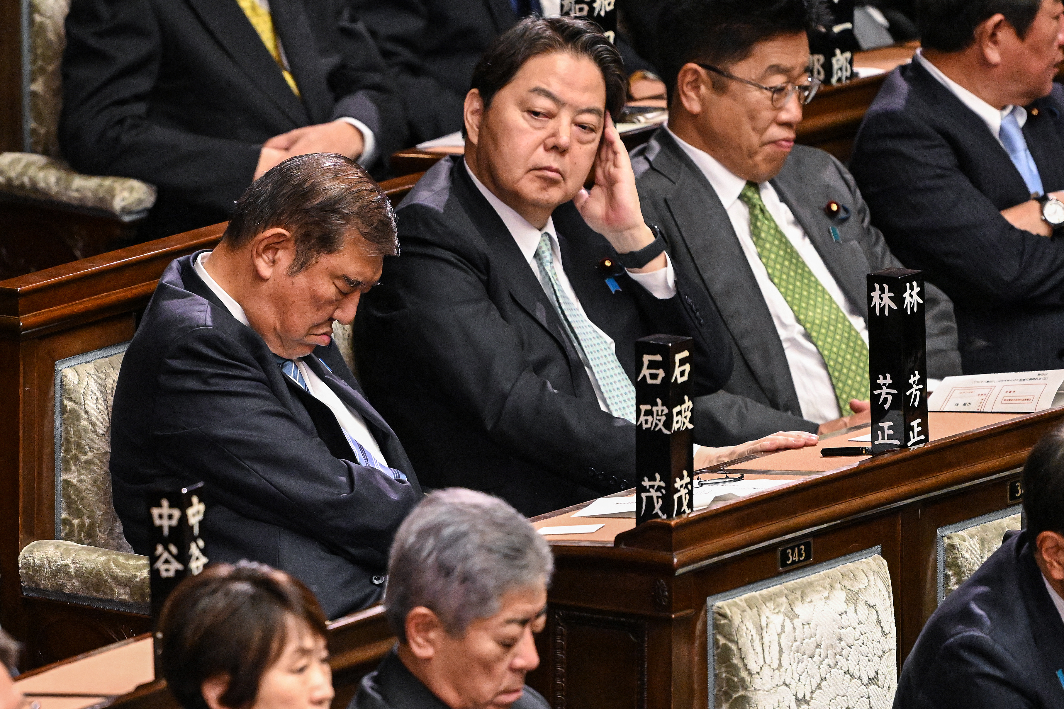 日本首相石破茂(左一)11日在眾議院首相指名選舉期間，一度雙眼閉著低頭看似打盹，因而引發熱議，事後官方澄清是吃了感冒藥。(AFP)