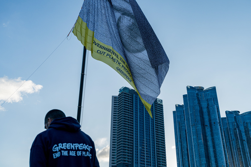 綠色和平全球團隊與國際行動藝術家阿契爾（Dan Acher）合作，25日在全球塑膠公約談判場外升起一面長30公尺、寬24公尺的「萬眾矚目」（We are watching）巨型旗幟，表達「全球公民都正看著」。（綠色和平提供） (圖：中央社)