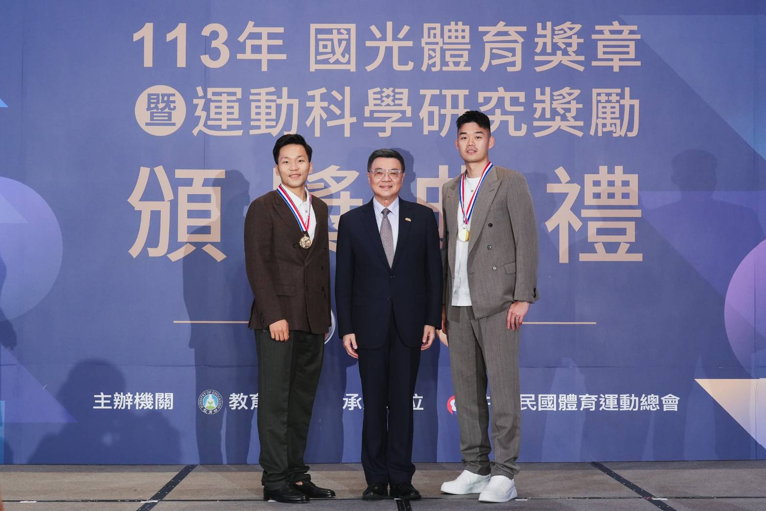 行政院長卓榮泰(中)6日出席「113年度國光體育獎章暨運動科學研究獎勵頒獎典禮」，並為奧運金牌李洋(左)、王齊麟(右)等人頒發國光獎章。(江昭倫 攝)