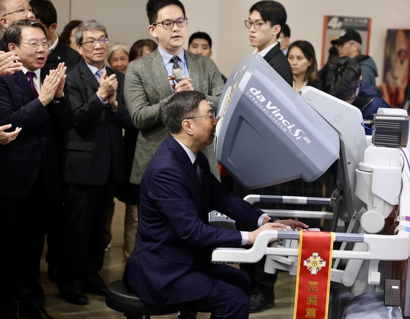 行政院長卓榮泰（前中）8日上午到台北南港展覽館1館參觀台灣醫療科技展，親自體驗操作精密機械手臂。(圖：中央社)