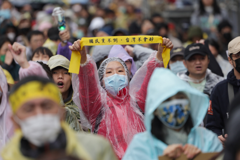 冬季青鳥公民行動20日在立法院濟南路集結，抗議藍白立委強推選罷法，參與民眾不畏雨勢穿上雨衣，舉標語表達立場。 (圖：中央社)