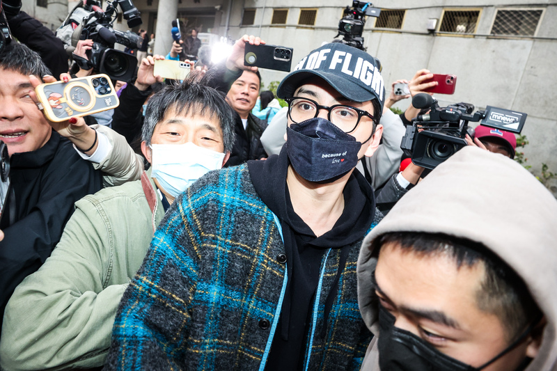新北地檢署偵辦妨害兵役案件，18日指揮刑事局等搜索藝人王大陸(黑帽者)住家，下午王大陸被帶到新北檢複訊後，檢察官諭令新台幣15萬元交保。圖為王大陸面對媒體提問不發一語。(圖：中央社)