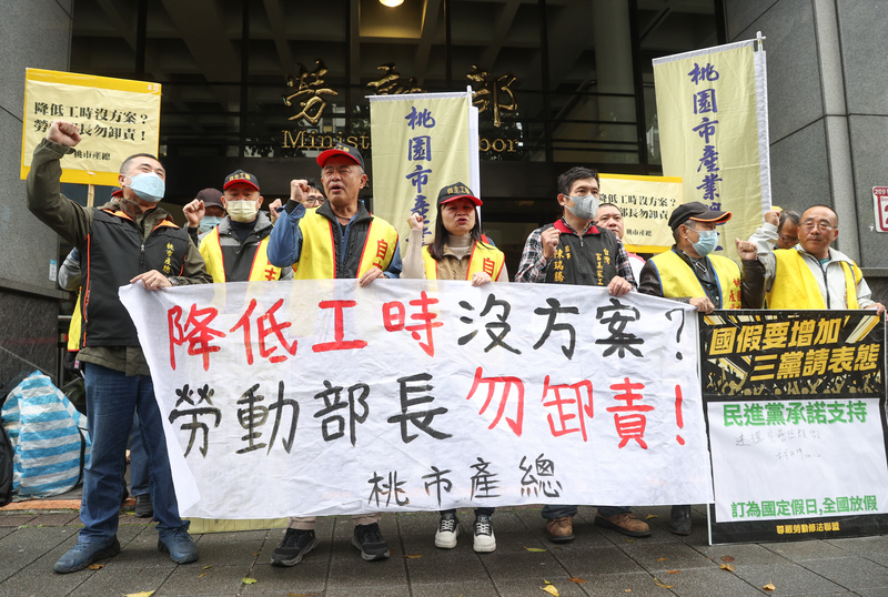 桃園市產業總工會等團體6日在勞動部前舉行記者會，與會者高呼「降低工時沒方案、勞動部長勿卸責」等口號表達訴求。(圖：中央社)