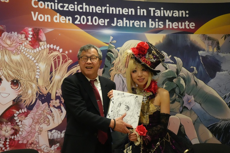 擅長少女漫畫題材、同時也是專業Coser的陳漢玲（右），是台灣少女漫畫創作代表人物之一，目前任教於台南應用科技大學漫畫系。她於訪德期間與駐德代表謝志偉見面，並致贈漫畫予台北駐德代表處。(圖：中央社)