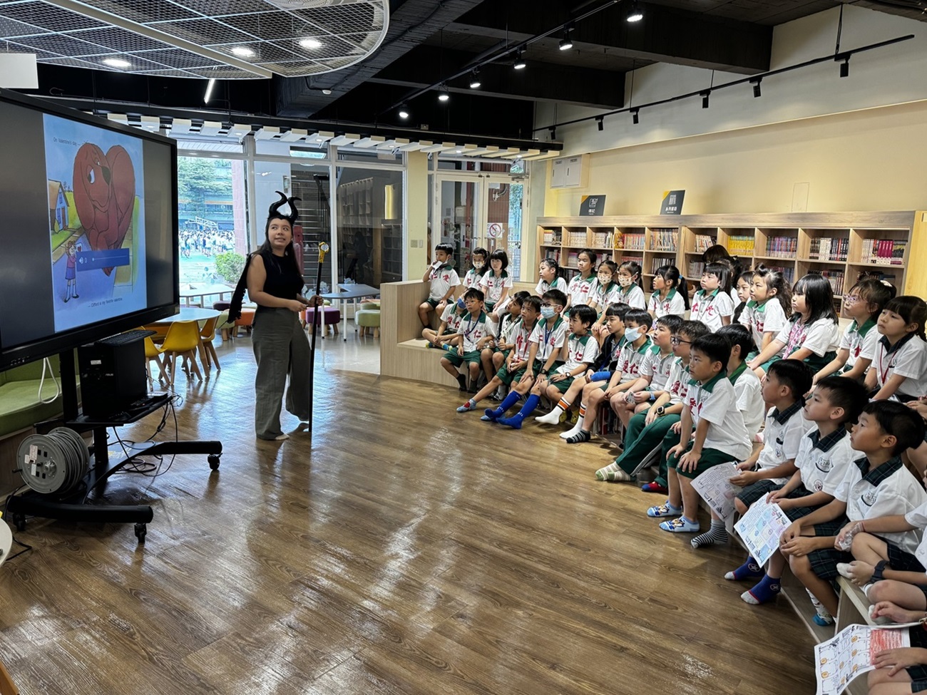 在台北市仁愛國小，部分工時外籍英語教學助理以生動有趣的方式，在圖書館「英語小書蟲故事屋」帶領學生閱讀英語繪本。(圖：教育部)