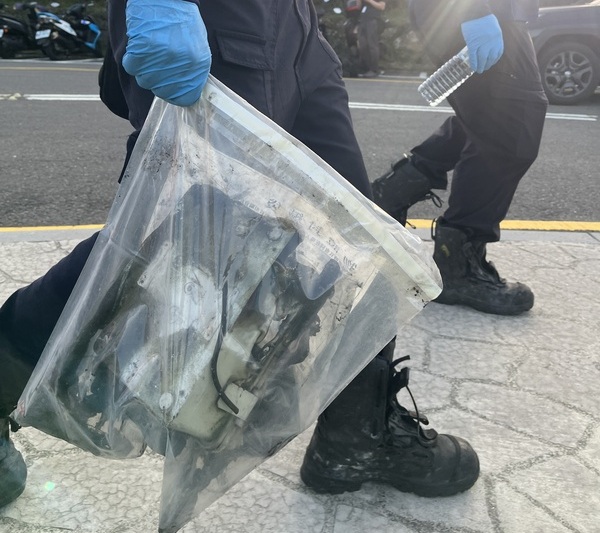 陽明山國家公園七星山步道區域14日上午11時許發生火災，初判為空氣品質感測儀器起火，已貼告示提醒民眾勿進入小油坑區域。鑑識人員拿著燒毀的證物下山，表示要拿回去鑑定。 (圖：中央社)