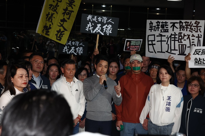 台北地檢署偵辦不實連署案，17日約談國民黨北市黨部主委黃呂錦茹等人，黨中央晚間號召赴北檢外聚集，台北市長蔣萬安（中灰衣者）也現身，手持麥克風向群眾喊話。 (圖：中央社)