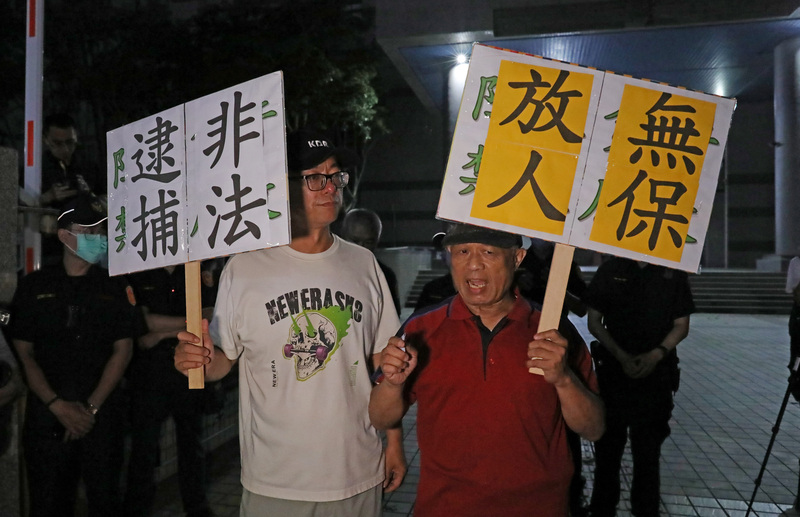 高雄「雙罷劫連署總站」負責人徐尚賢涉不實連署案遭聲押，徐尚賢父親（前右）與罷免案領銜人之一的朱磊（前左）等人19日晚間到高雄地檢署關心偵辦進度，高喊非法逮捕、無保放人等口號。(圖：中央社)