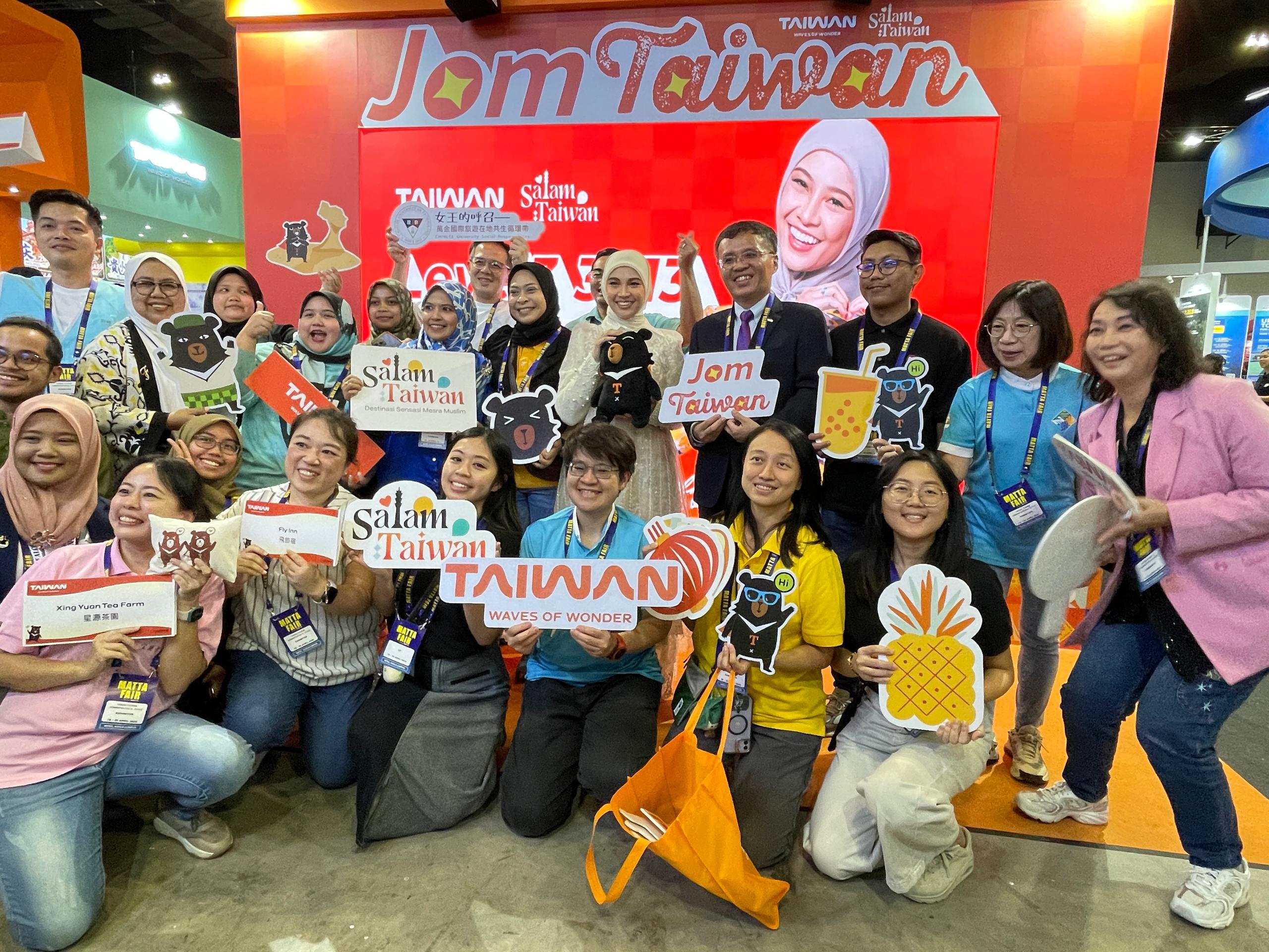 周士弼與娜比拉在馬國國際旅遊展與台灣旅遊業者合照。(陳億佩攝)