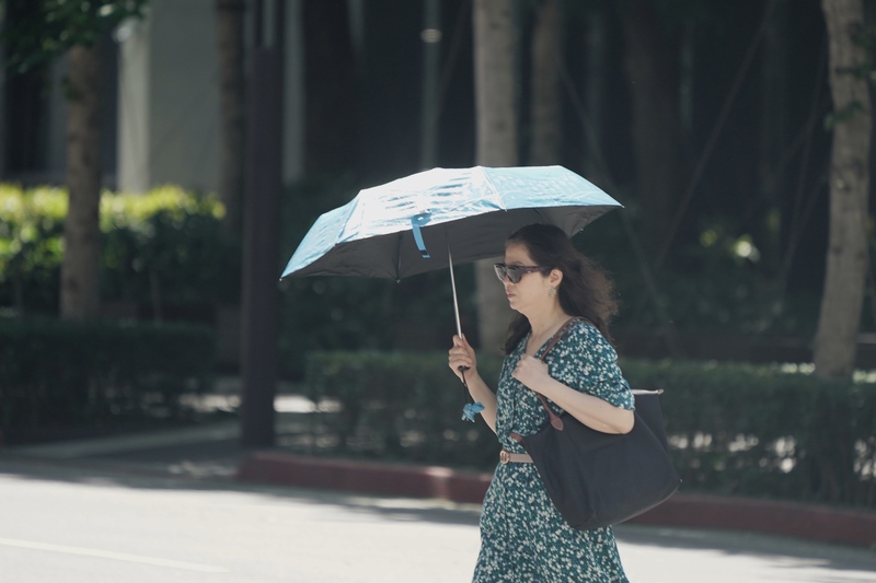 氣象署22日針對雙北、南高屏、台東發布高溫燈號。圖為一位民眾22日上午走在台北市中正區街頭撐傘遮陽。(圖：中央社)