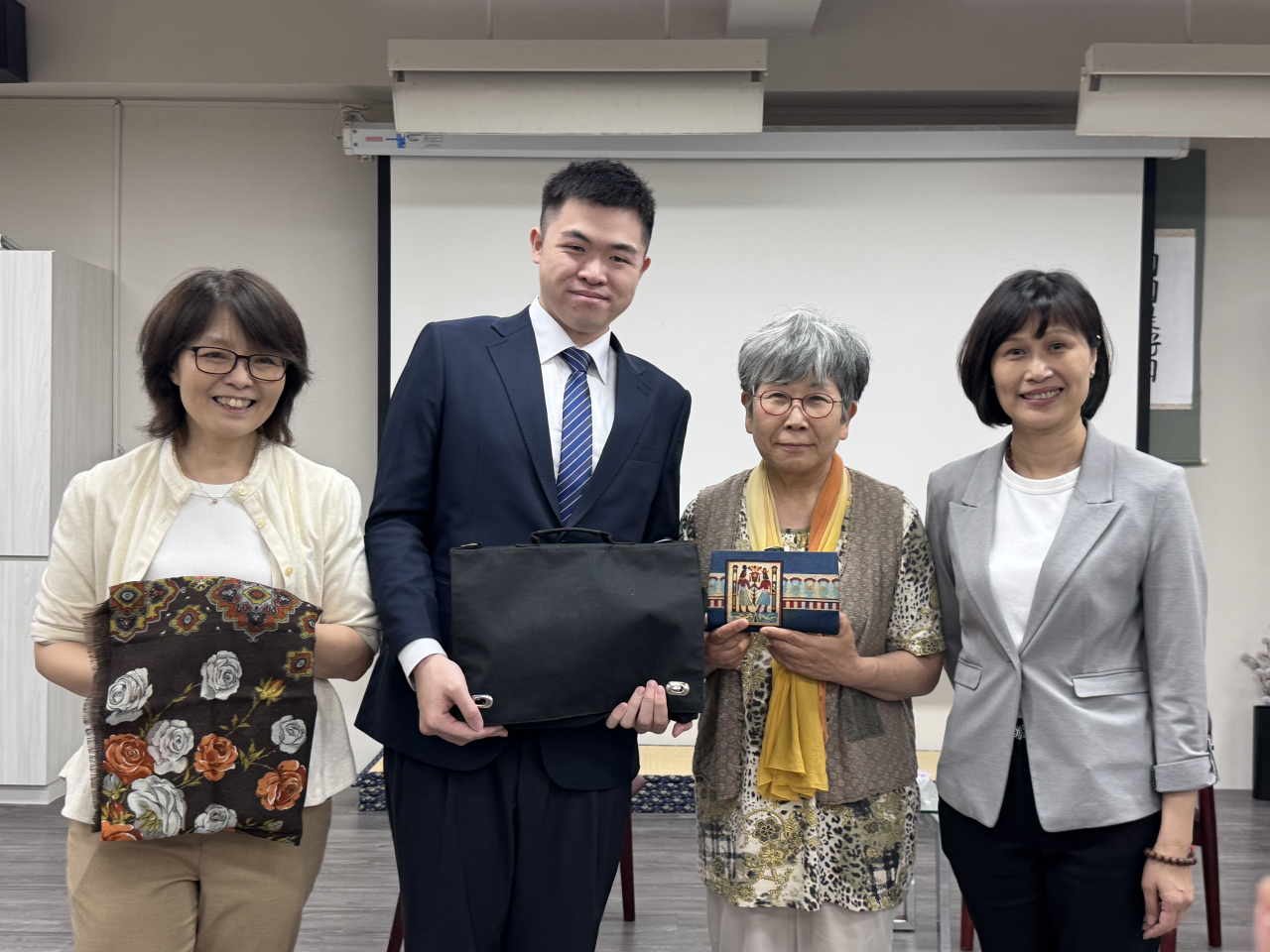 伊東優里（右二）從台北城市科技大學應用外語系主任陳乃慈（左）手中接過父親親手繡製的包，難掩欣喜。左二為代替伊東香保領回失物的畢業生蕭博允，右為該校校長馮美瑜。(豐田楓蓮 攝)