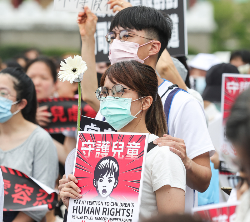 「終結兒虐．陪你長大」護兒集會行動10日下午在凱達格蘭大道舉行，與會民眾手持花朵和「守護兒童」標語到場支持活動理念。 (圖：中央社)